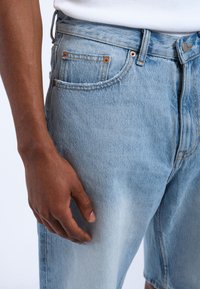 Lichtblauwe denimshorts met een vervaagde uitstraling, voorzien van koperen klinknagels, een knoopsluiting en een klassieke vijfzakkenontwerp.