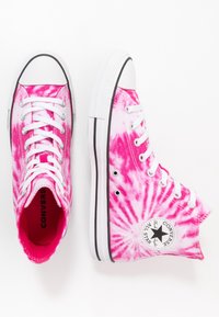 Pár růžovo-bílých sneakers vysokého střihu Converse s bílými tkaničkami a gumovými podrážkami na bílém pozadí.