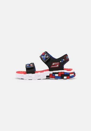 Black sandal with adjustable straps, red and blue accents, white sole, and a textured, colorful patterned footbed.