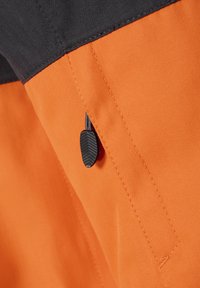 Oranžinis zigzago rašto audinys su juoda viršutine dalimi. Yra tekstūruotas juodas traukimo antras su užtrauktuku uždaromu kišenėje saugiam uždarymui.