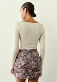 Ilgi piedurkņu gaiši brūns tops ar plašu kakla izgriezumu, kas saskaņots ar ziedu mini svārkiem tumšās krāsās ar rozā un baltām ziedu motīviem.