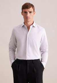 Camicia bianca con strisce viola chiare, maniche lunghe e colletto a bottoni, abbinata a pantaloni scuri con texture e tasche laterali.