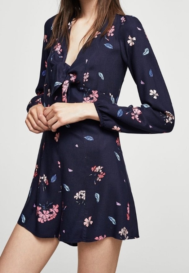 Robe fleurie marine à manches longues, décolleté en V et détail nœud à la taille. Présente des motifs floraux roses et verts sur un tissu doux.