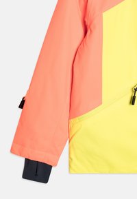 Ärm och sidopanel av en jacka med korallrosa och gula färgblock, med en diagonal dragkedja och svart innerhandled.