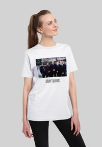 Bílý tričko se barevným fotografií pěti mužů v oblecích, s textem „sopranos“ v šedé barvě pod obrázkem.