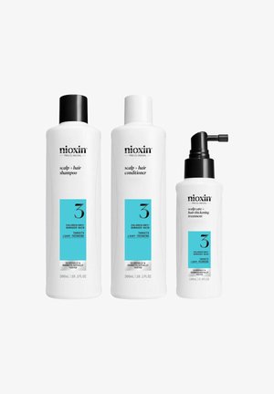 Nioxin hair care set with three white bottles: shampoo, conditioner, and treatment. Each labeled with blue accents, targeting colored, dry hair.