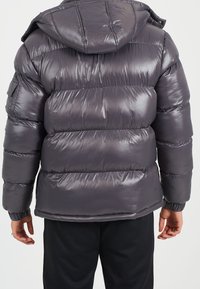 Puffjacka i glänsande mörkgrått material med horisontella läderstycken, en passformshuva och elastiska mudd för värme och komfort.