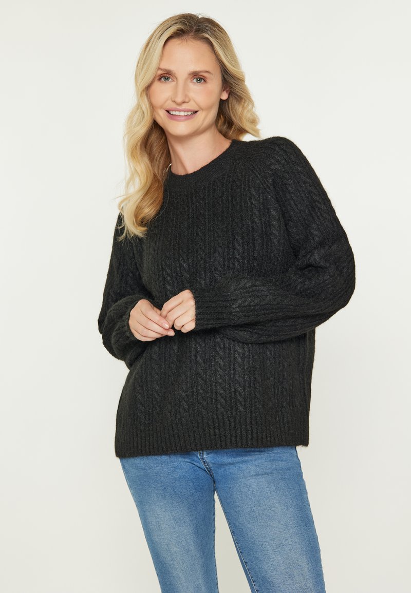 Pulover închis, tricotat, cu textură ribbed, guler rotund și mâneci lungi. Asortat cu blugi din denim albastru deschis.
