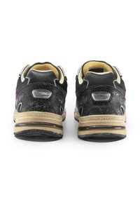 Sneaker nere con un retro testurizzato, dettagli rosa e una suola in gomma beige, con un logo inciso sul tallone.