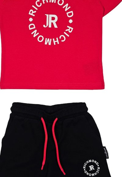 T-shirt rossa con logo circolare bianco e testo "JR", abbinata a pantaloni della tuta neri con cordoncino rosso e dettaglio logo simile.