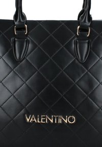 Bolso tote de cuero negro acolchado con el logo dorado "VALENTINO". Presenta dos asas para el hombro y costuras en patrón de diamante.