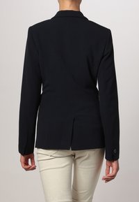 Blazer noir au design ajusté, manches longues, revers cranté et fente simple à l'arrière. Tissu élégant avec une texture lisse.
