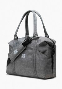 Sac de voyage en tissu gris avec deux poignées, sangle d'épaule réglable, poches avant et patch rectangulaire avec logo sur le côté.