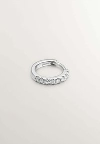 Anillo de plata con una fila de piedras preciosas circulares transparentes engastadas en una banda decorativa. Superficie lisa con un acabado pulido.