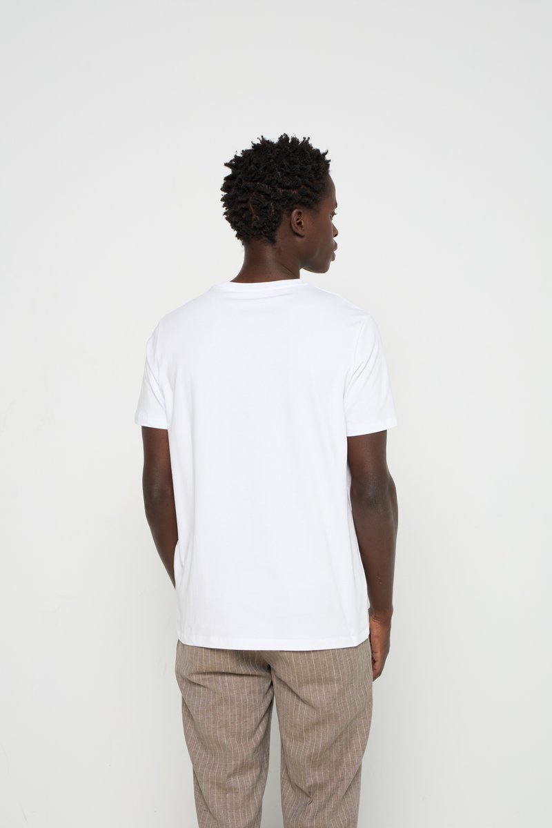 Camiseta de algodón blanca con mangas cortas, escote redondo y un corte relajado, combinada con pantalones de rayas color marrón claro.