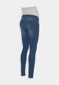 Jeans de maternidad en denim azul oscuro con una cinturilla elástica gris. Cuenta con un corte ajustado, bolsillos traseros y detalles de costura sutiles.