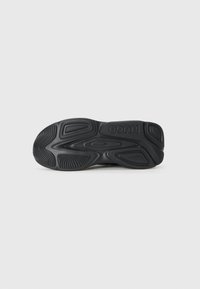 Black athletic shoe sole with a textured rubber surface, featuring multiple grooves and patterns for grip and flexibility. HUGO logo present.