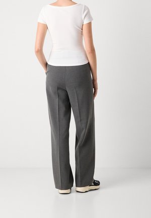 Witte aansluitende top met korte mouwen, gecombineerd met grijze, op maat gemaakte broek met wijde pijpen. Gladde stof met subtiele textuur, neutrale kleuren en eenvoudig ontwerp.