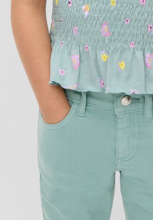 Lichtgroene top met korte mouwen, versierd met bloemen- en vlinderpatronen; gecombineerd met bijpassende groene broek. Soepele stof, elastische taille en ruchesdetails.