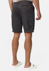 Shorts en coton gris foncé avec revers roulés, dotés d'une poche arrière avec bouton et d'un petit accent d'étiquette près de la ceinture.