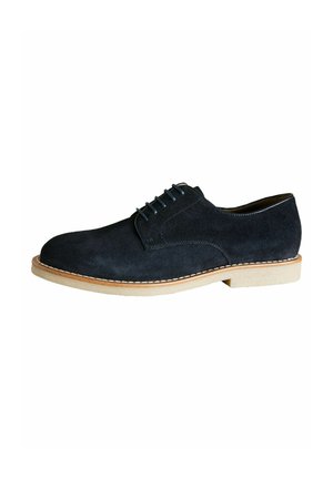 Zapato de vestir de ante azul oscuro con parte superior lisa, detalle de costura, suela de goma de color claro y cierre de cinco cordones en el empeine.