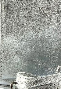 Zilveren handtas met een gestructureerde textuur, gemaakt van glanzend materiaal met een gladde afwerking, voorzien van een band met kleine gaatjes en een metalen gespaccent.