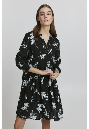 Zwarte jurk met een bloemmotief in lichtblauw en wit. Voorzien van een knoopsluiting aan de voorkant, kraag en lange, opgezette mouwen. Uitlopende zoom.