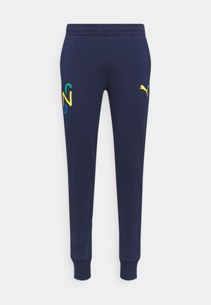 Pantalon de survêtement bleu marine avec taille et poignets élastiques, logo Puma jaune sur la cuisse droite, "N" stylisé multicolore sur la cuisse gauche.