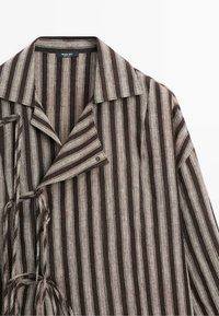 Chemise boutonnée à rayures verticales marron et beige avec col et détails de liens sur les côtés, en tissu texturé.