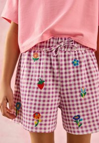 Roze geruite shorts met kleurrijke bloemenborduursels. Voorzien van een elastische tailleband en trekkoord. Gemaakt van lichtgewicht, ademend materiaal.