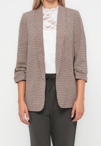 Marynarka w beżowo-ciemnobrązowy wzór pepitki, wykonana z lekkiego materiału, z otwartym przodem i podwiniętymi rękawami do połowy przedramienia.