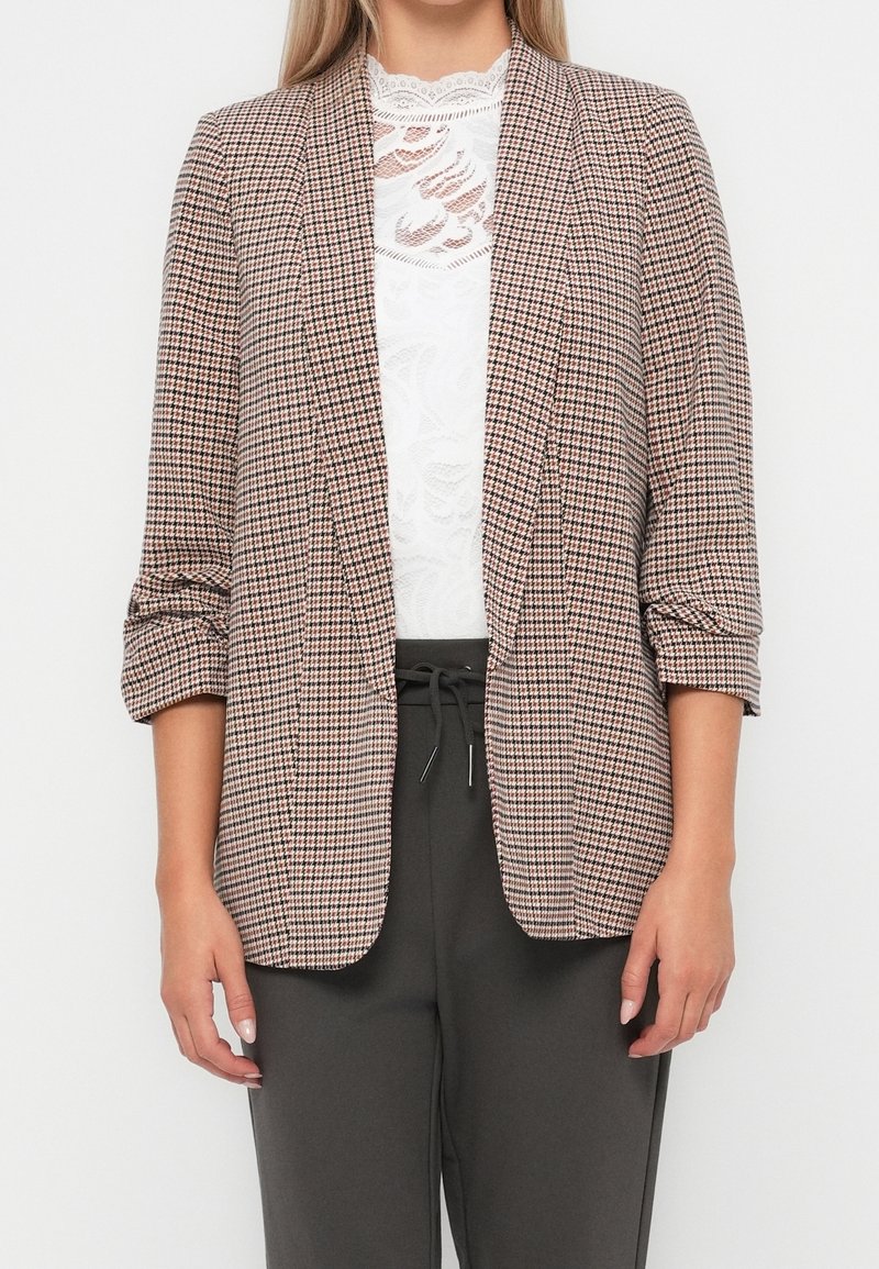 Marynarka w beżowo-ciemnobrązowy wzór pepitki, wykonana z lekkiego materiału, z otwartym przodem i podwiniętymi rękawami do połowy przedramienia.