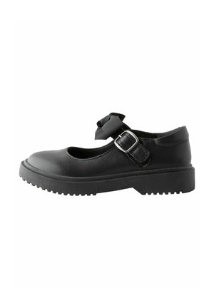 Zapato Mary Jane de cuero negro con punta redonda, suela de goma plana, correa al tobillo y detalle decorativo de lazo. Acabado texturizado con hebilla ajustable.