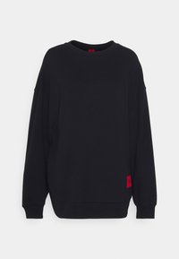 Svart sweatshirt med rund halsringning, sänka axlar och långa ärmar. Har en liten röd etikett på nedre vänstra sidan. Mjuk tygkvalitet.