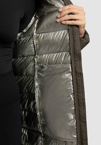 Kurtka puchowa z ciemnym wykończeniem i błyszczącym metalicznym srebrnym podszewką. Posiada pikowaną teksturę oraz wewnętrzną kieszeń.