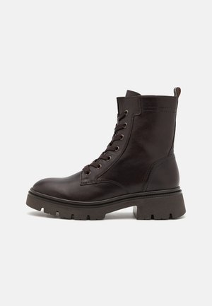 Brown leather combat boots with a lace-up design, rugged outsole, rounded toe, and pull tab at the back for easy wear.