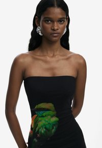 Black strapless dress featuring a colorful bird print on the front. Smooth texture, fitted shape. Model wears large silver earrings.