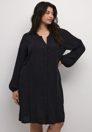 Vestido negro de botones, hecho de una tela ligera, con mangas largas, escote en V y un intrincado detalle de encaje a lo largo de los costados.