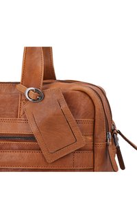 Borsa in pelle marrone chiaro con superficie testurizzata, scomparti con doppia cerniera e un'etichetta per bagagli attaccata che presenta una forma rettangolare e bordi cuciti.