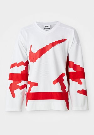 Vit långärmad tröja med röda grafiska inslag inklusive en stor Nike-logotyp, med ett nättextur och kontrasterande horisontella röda ränder.