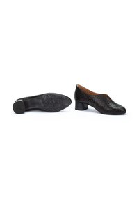 Chaussures en cuir perforé noir avec un bout rond et un petit talon. La semelle présente un motif texturé pour une meilleure adhérence.