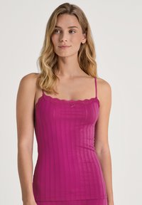 Fuchsia ribbed camisole with thin straps, lace trim along the neckline, and a small bow detail at the center. Soft, textured fabric.