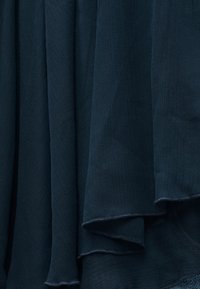 Σκούρο μπλε ριγωτό ύφασμα με διπλωμένες στρώσεις, που εμφανίζει λεπτή κάθετη υφή και μαλακά, διπλωμένα άκρα.