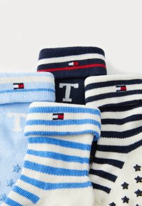 Quattro paia di calzini: blu chiaro con stelle, navy a righe e a righe alterne blu e bianche, con accenti di logo.