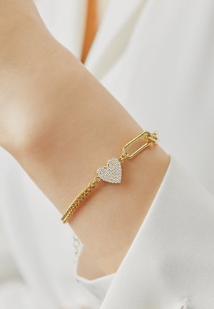Goldkette Armband mit einem Herzanhänger, der mit klaren Strasssteinen verziert ist. Verstellbare Länge mit einem Klappschnellverschluss. Einfaches und elegantes Design.