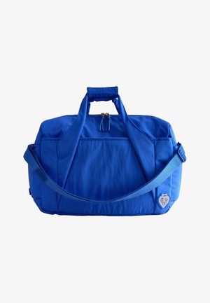 Sac de voyage rectangulaire bleu vif avec poignées, bandoulière réglable, fermeture éclair frontale et petit emblème en forme de cœur dans le coin inférieur droit.