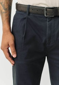 Navy trousers made of soft fabric with a smooth texture, featuring front pleats and a dark brown belt with a metal buckle.