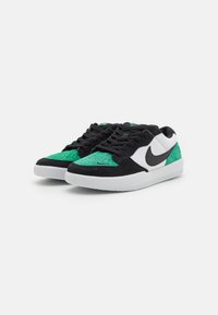 A fekete és zöld velúr tornacipők fehér bőr swoosh-t tartalmaznak, kontrasztos textúrák, párnázott nyelv és fehér gumitalp jellemzi őket.