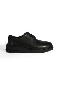 Zwarte leren schoenen met een gladde afwerking, ronde neus en een gestructureerd vetersysteem. Voorzien van een dikke zwarte zool met verende accenten.