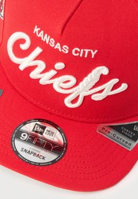 Casquette snapback rouge avec broderie "Kansas City" et "Chiefs" en blanc. Le matériau est en tissu avec une visière pré-incurvée ; l'étiquette affiche la marque 9FIFTY.